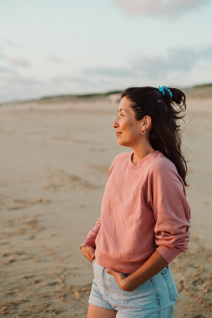 Frau steht im Sonnenuntergang am Strand