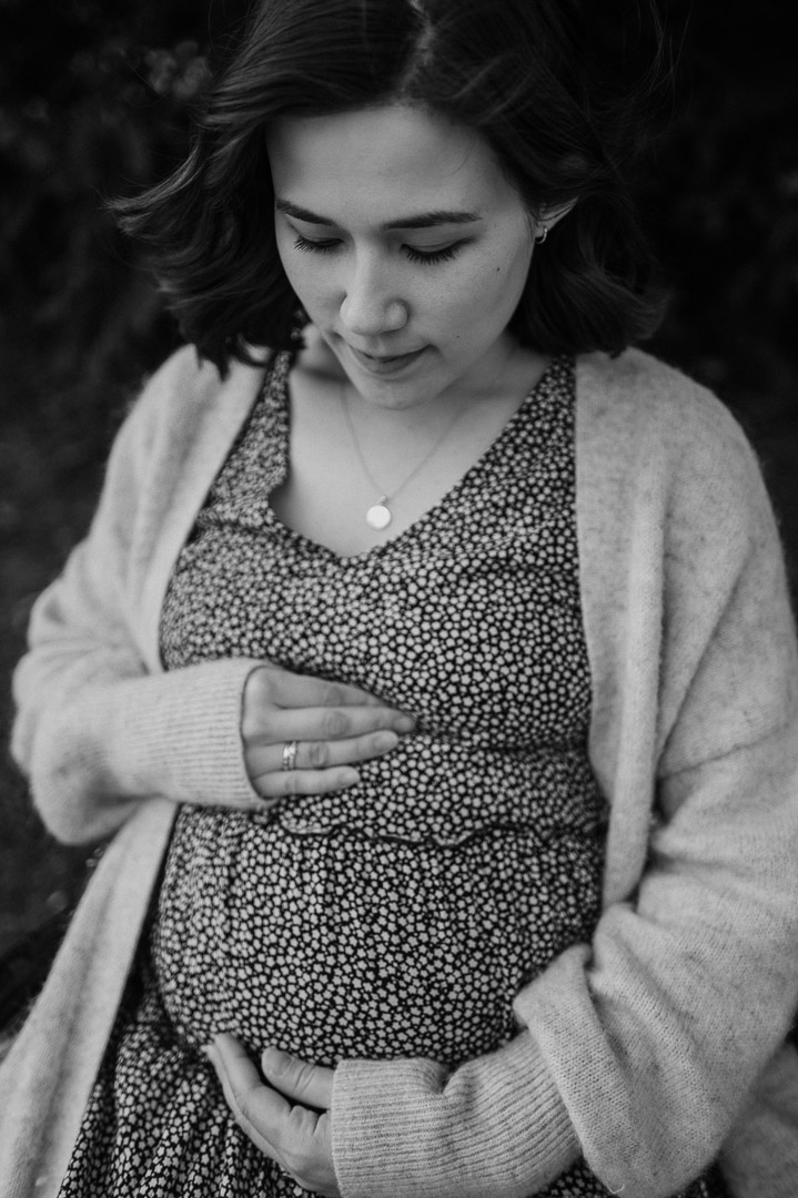 Schwangere hält ihren Babybauch mit geschlossenen Augen