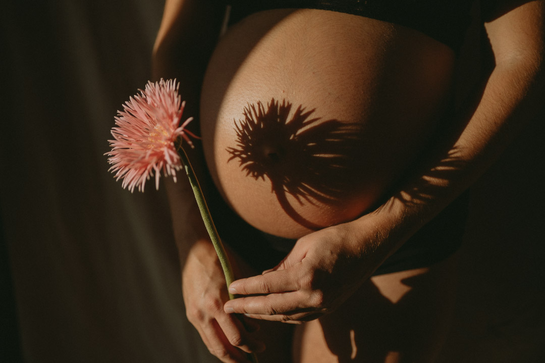 Blume wirft Schatten auf Babybauch