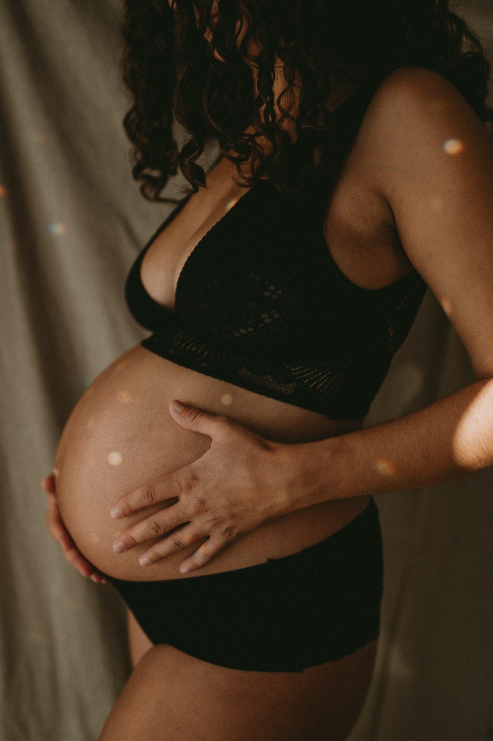Schwangere in Unterwäsche hält ihren Babybauch