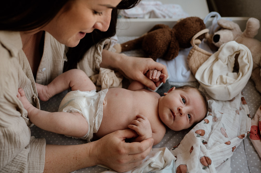 Mama spielt mit Baby in Windeln auf dem Wickeltisch