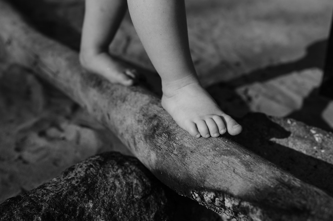 Kinderfüsse laufen auf Baumstamm