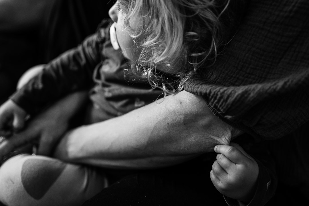 Kleinkind hält sich an Mamas Arm fest