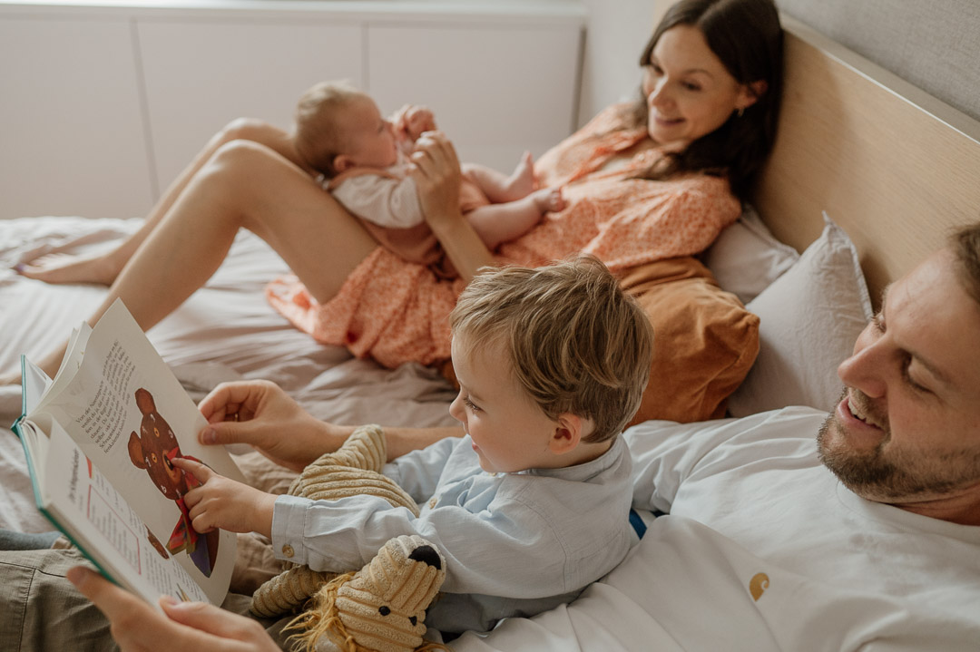 Familie kuschelt im Bett und liest ein Buch