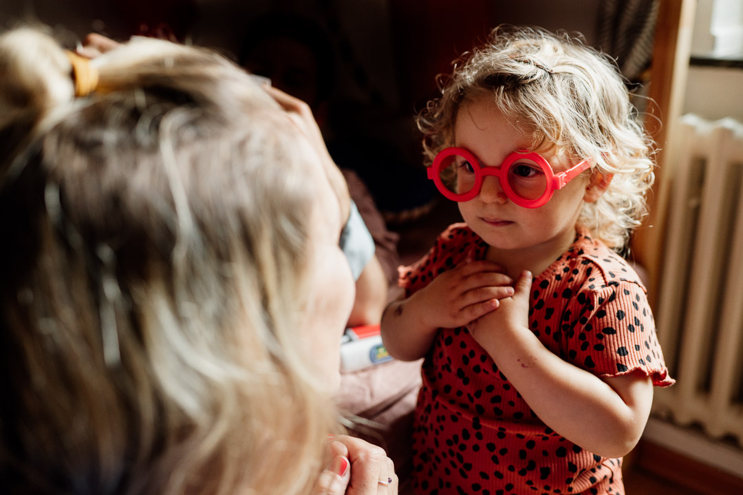 Kleinkind mit roter Brille betrachtet seine Mama