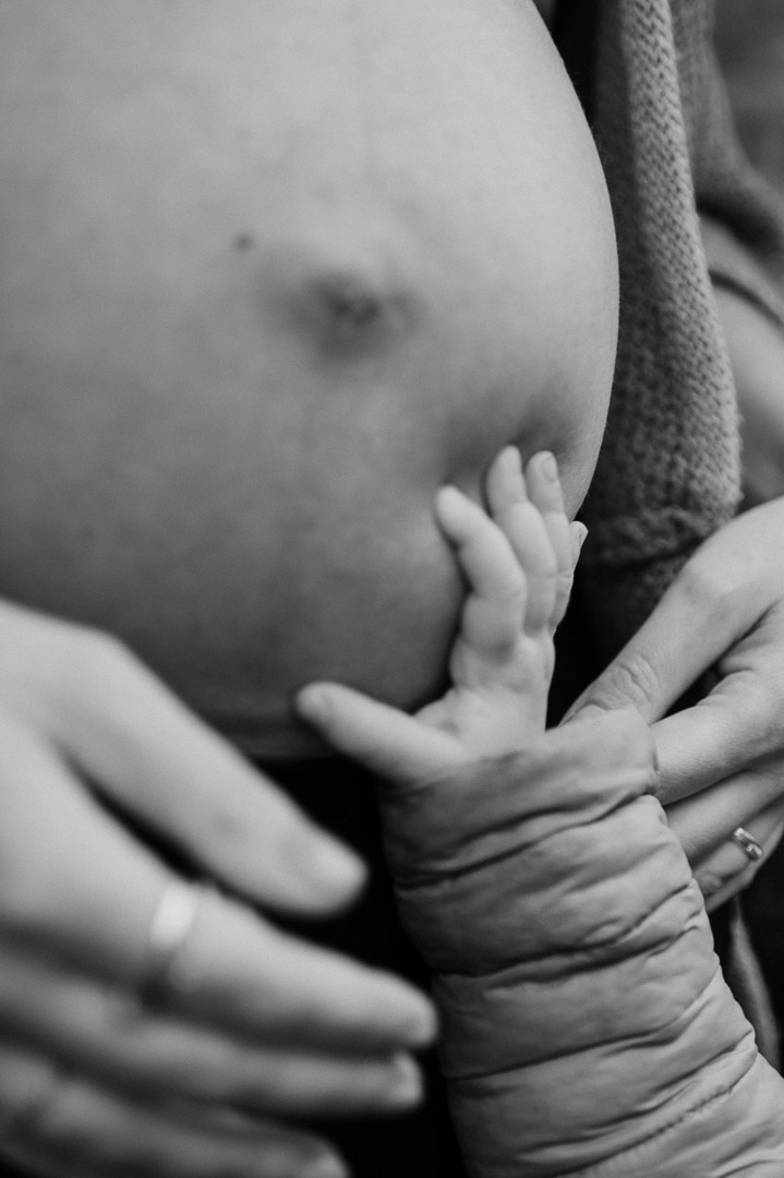 Kleinkindhand greift Babybauch