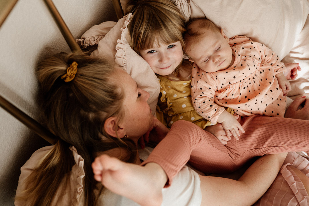 Kinder liegen bei Mama im Arm