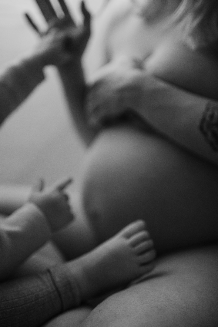 Kleinkindhand zeigt auf Babybauch