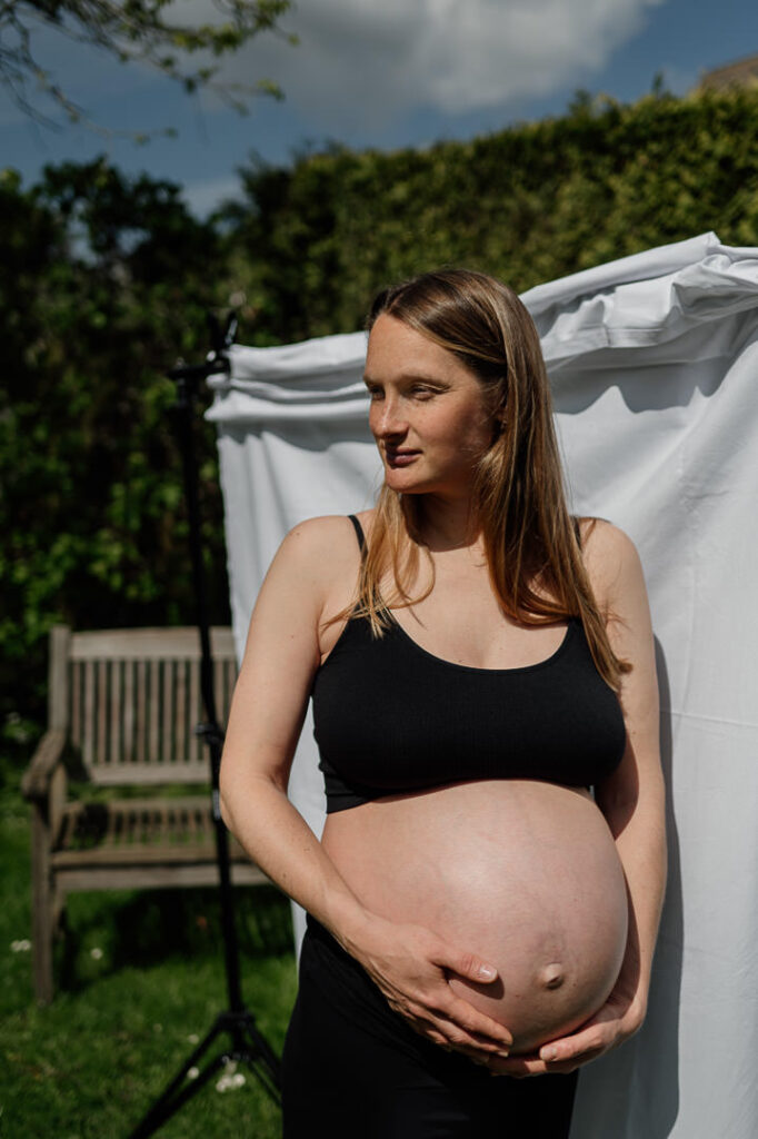 Schwangere steht bauchfrei in der Sonne