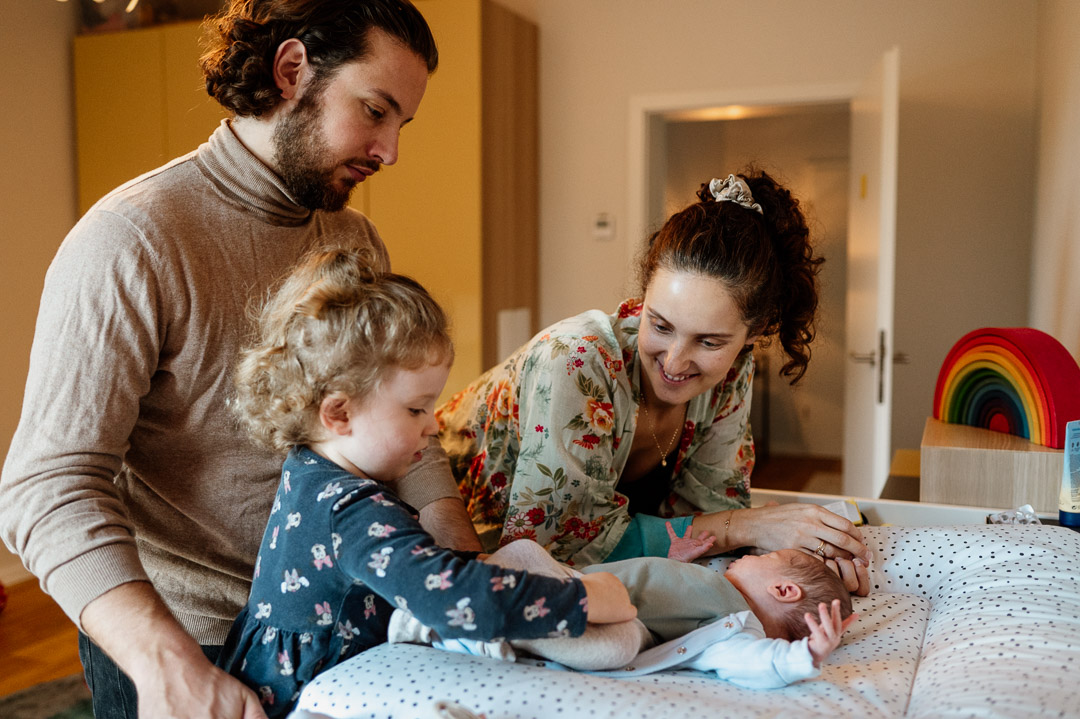 Mama Papa und große Schwester wickeln das Baby